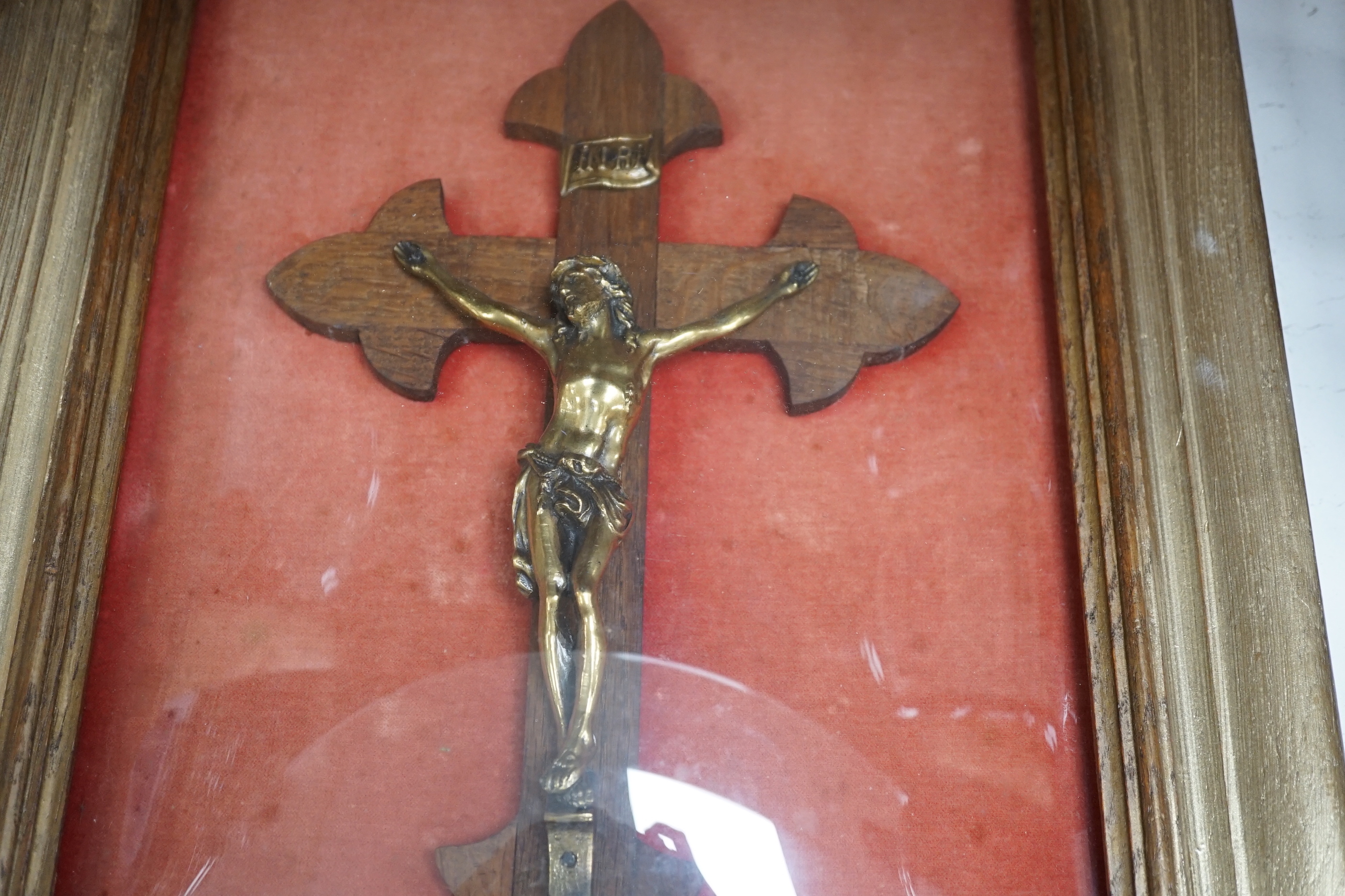 An oak and brass crucifix framed behind convex glass, overall 51cm x 37cm